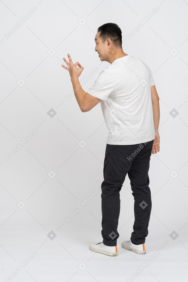 Side view of a happy man in casual clothes showing ok sign