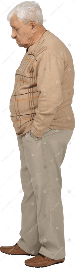 Vista lateral de un anciano con ropa informal de pie con las manos en los bolsillos