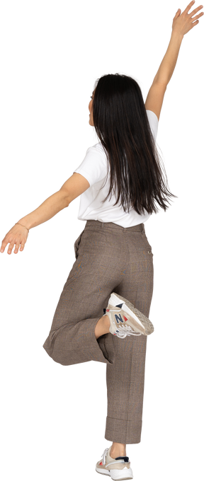 Rückansicht einer tanzenden jungen dame in reithose und t-shirt, die ihre hand ausstreckt