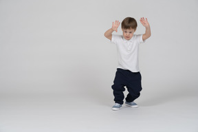 Front view of a boy squatting slightly with raised hands