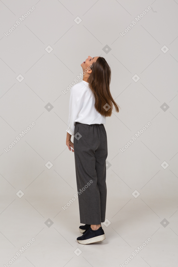 Three-quarter back view of a young lady in office clothing throwing head back