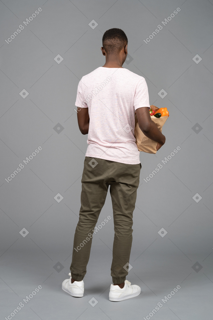 A young man carrying a grocery bag