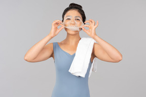 Young indian woman with white towel on shoulder peeling off face mask