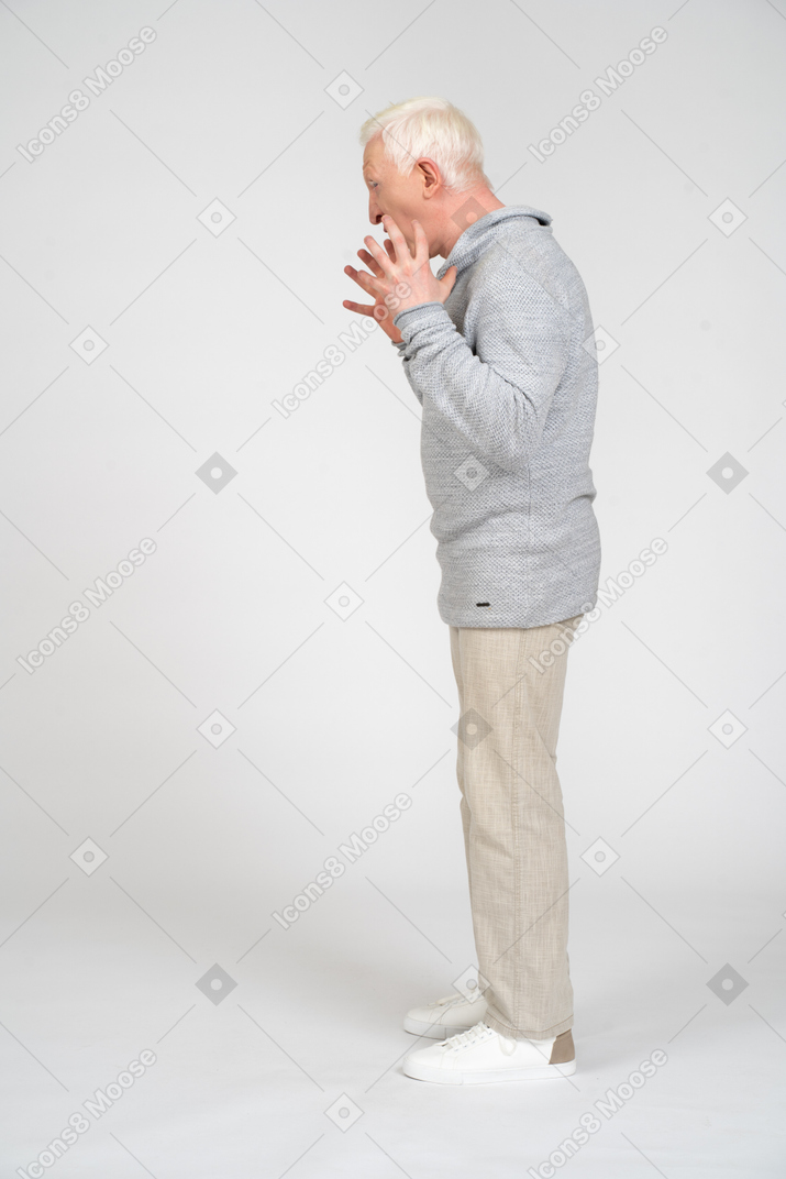 Vista lateral de un hombre de pie con los dedos extendidos y gritando