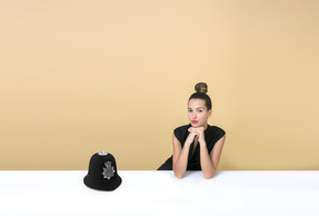 Giovane donna seduta a un tavolo vicino a un cappello della polizia