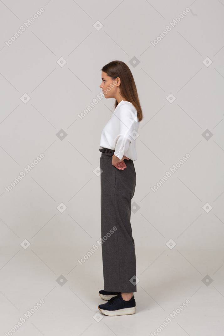一位身着办公室服装的年轻女士把手放在臀部的侧视图