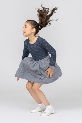 Three-quarter view of a girl smiling and squating while jumping