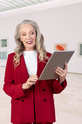 A woman in a red suit holding a tablet