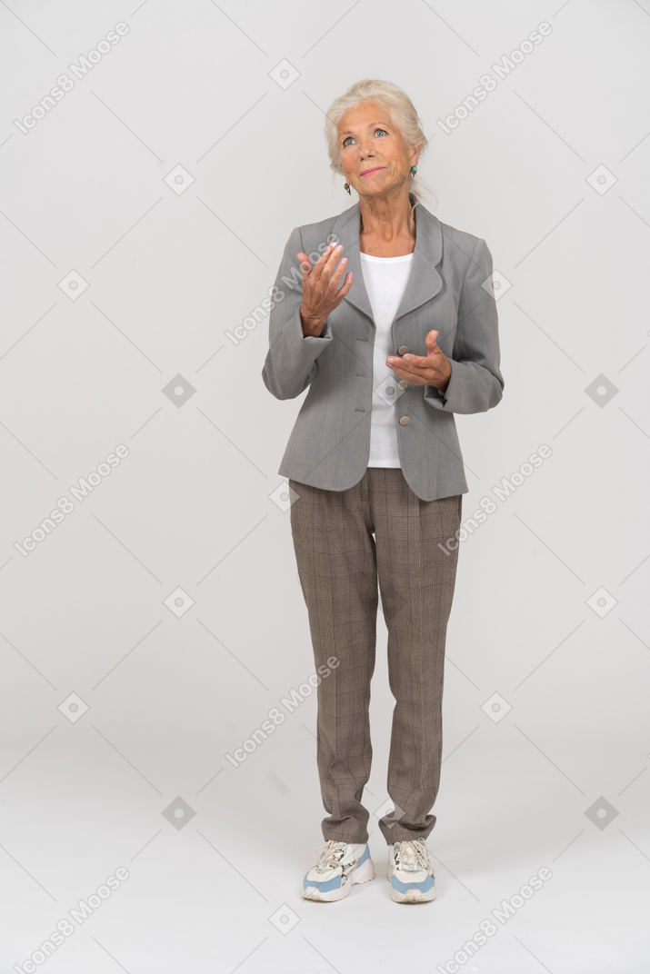 Vista frontale di una vecchia signora in abito che indica con la mano