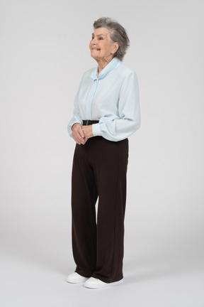 Vista laterale di una donna anziana che fa una smorfia con le mani giunte