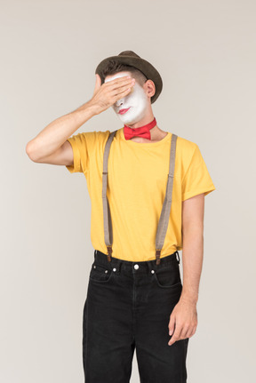 Male clown looking down and touching his forehead