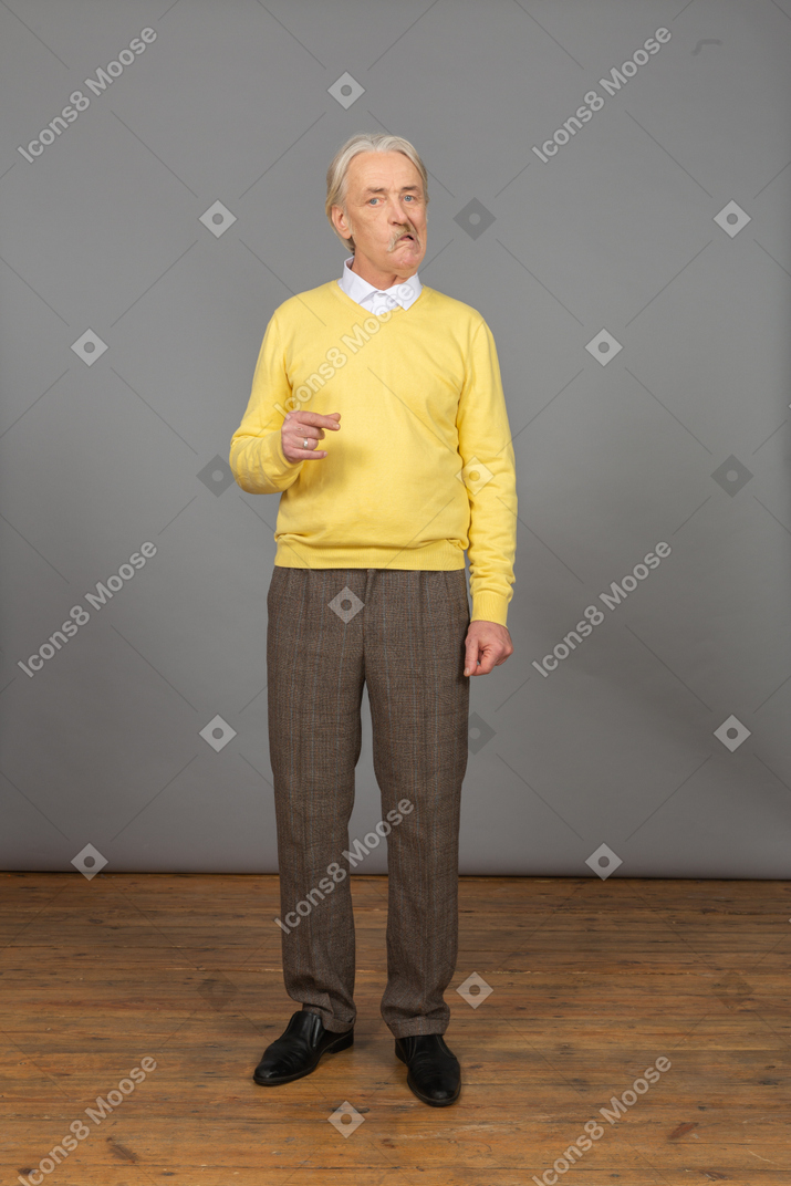 Vue de face d'un vieil homme ruse gesticulant et regardant la caméra