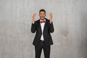 Amazed man in black suit holding up his hands