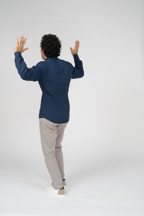 腕を上げて立っているカジュアルな服装の男性の背面図