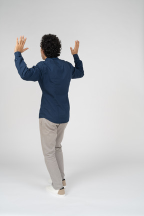 Rear view of a man in casual clothes standing with raised arms