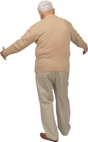 Vue arrière d'un vieil homme en vêtements décontractés debout avec les bras tendus