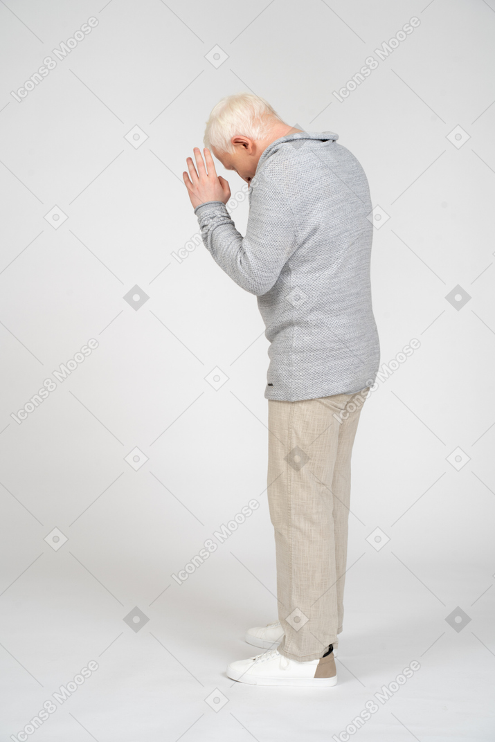手を祈りの位置に置いて立っている男性の側面図