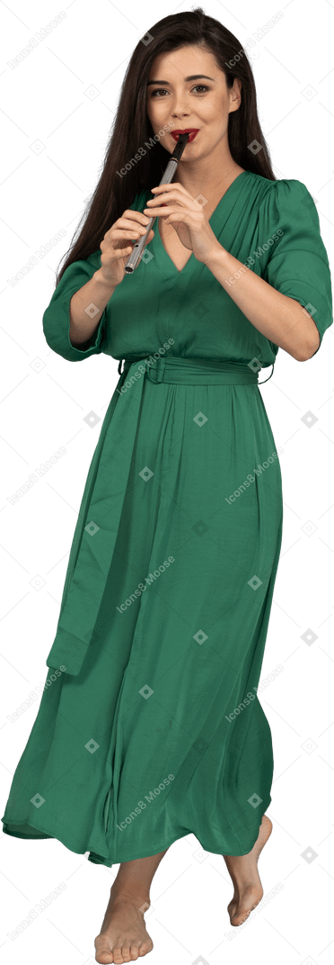 Front view of a walking young lady in green dress playing the flute