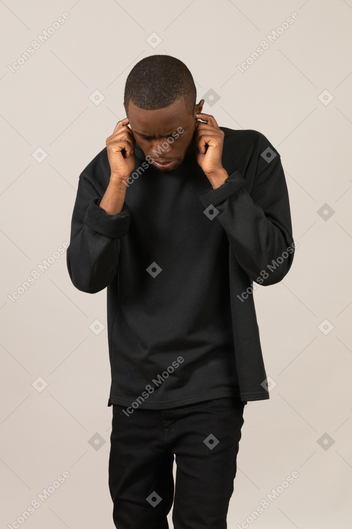 Man plugging ears and looking down