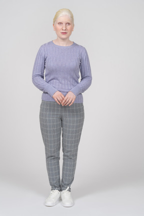 Vista frontale di una giovane donna in maglione lavanda e pantaloni grigi