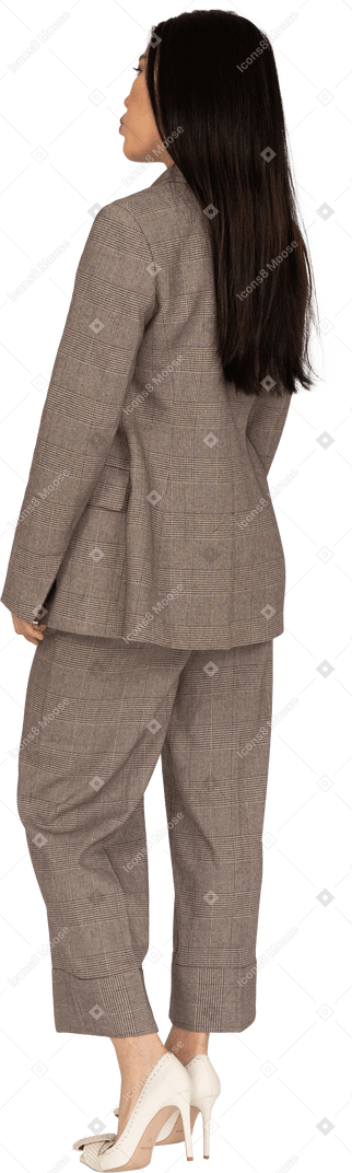 茶色のビジネススーツを着たふくれっ面の若い女性の4分の3の背面図