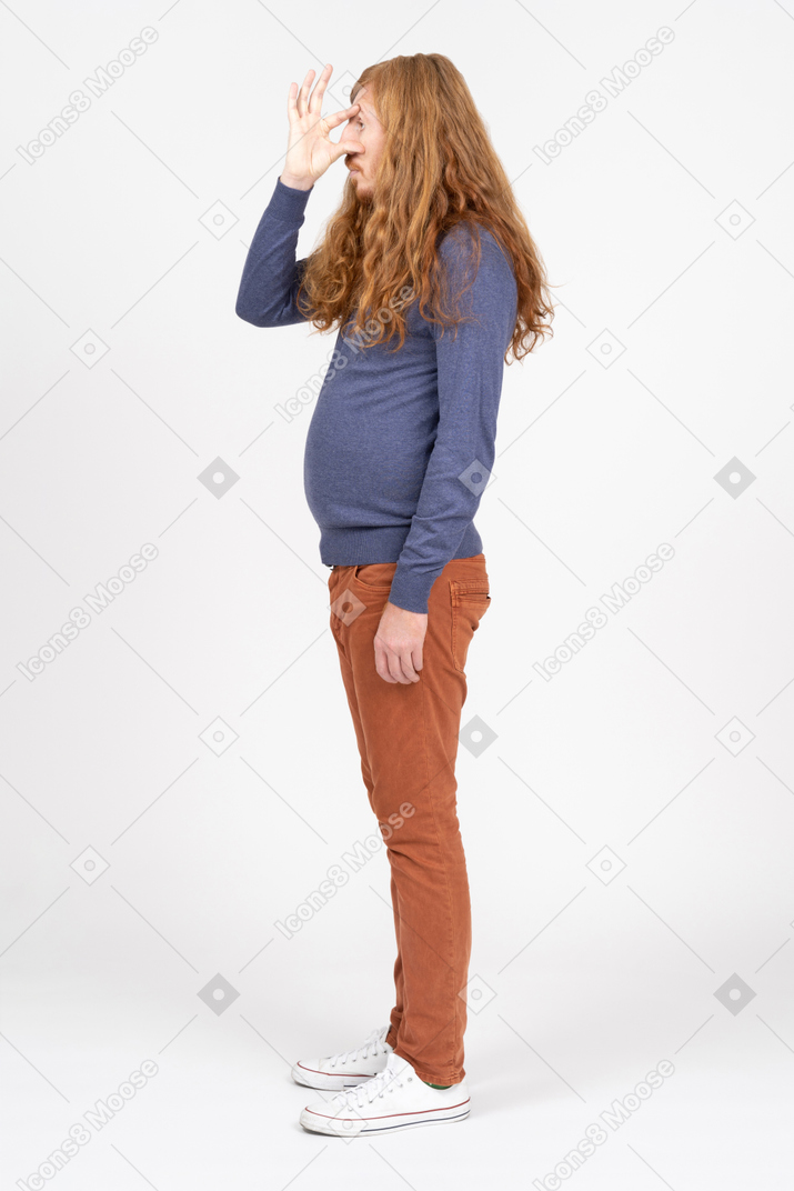 Vista lateral de um jovem em roupas casuais, olhando por entre os dedos