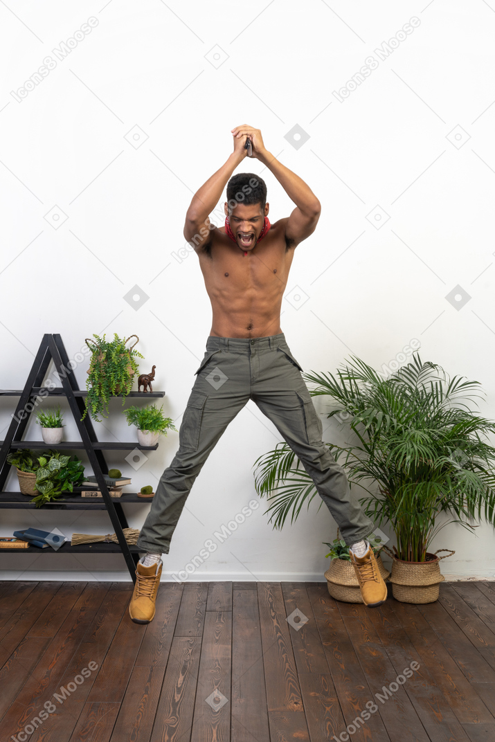 Muscular young man with a blade in raised arms jumping up