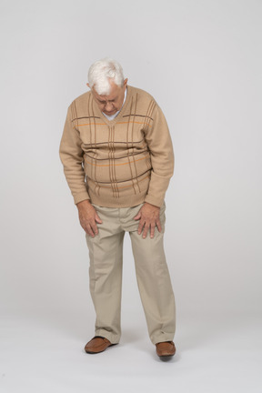 Vista frontal de um velho em roupas casuais, olhando para baixo