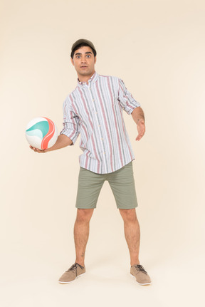 Surprised young caucasian guy holding ball