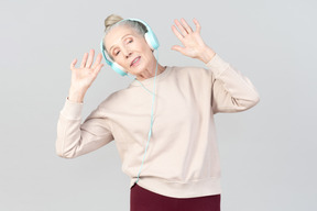 Jovencita alegre con auriculares bailando al ritmo de la música