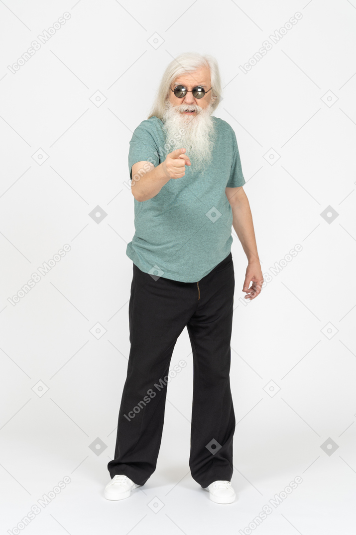 Front view of old man in sunglasses pointing at camera