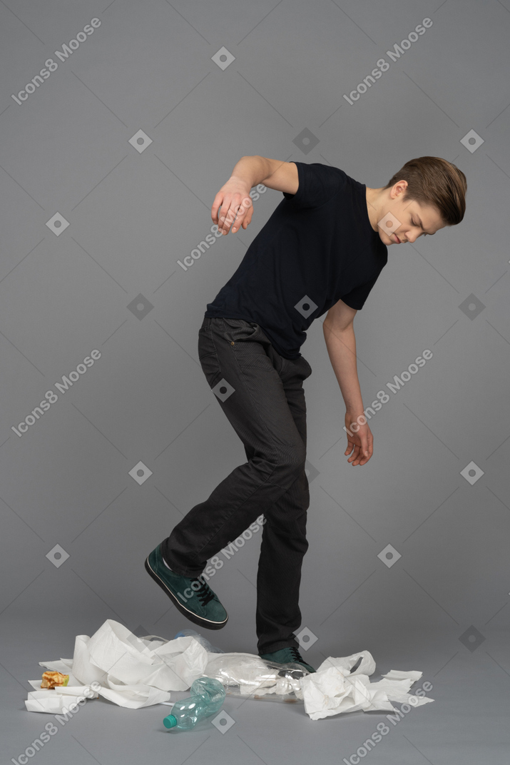 Man walking among garbage raises his leg and balancing