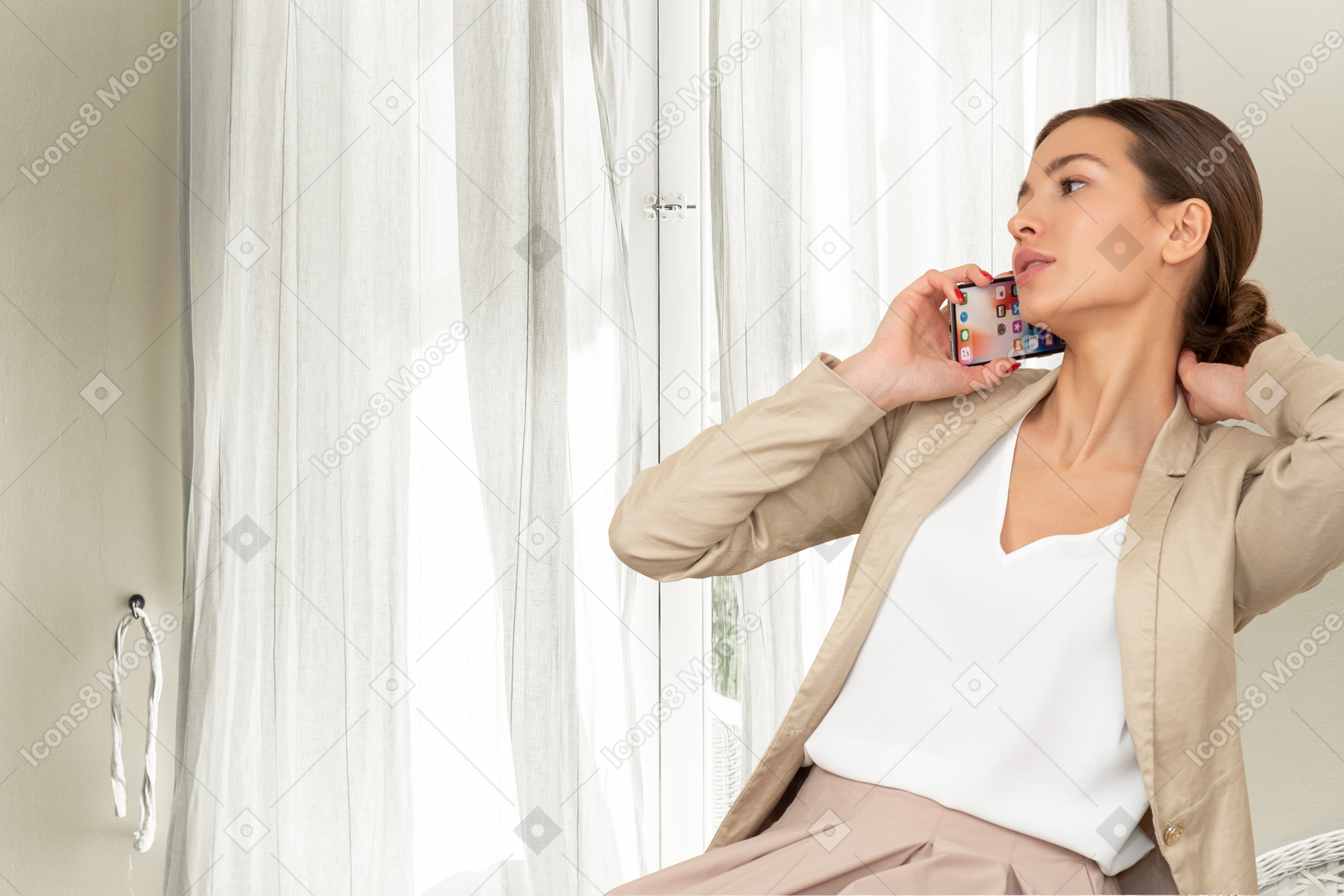 A woman sitting at the window talking on a cell phone
