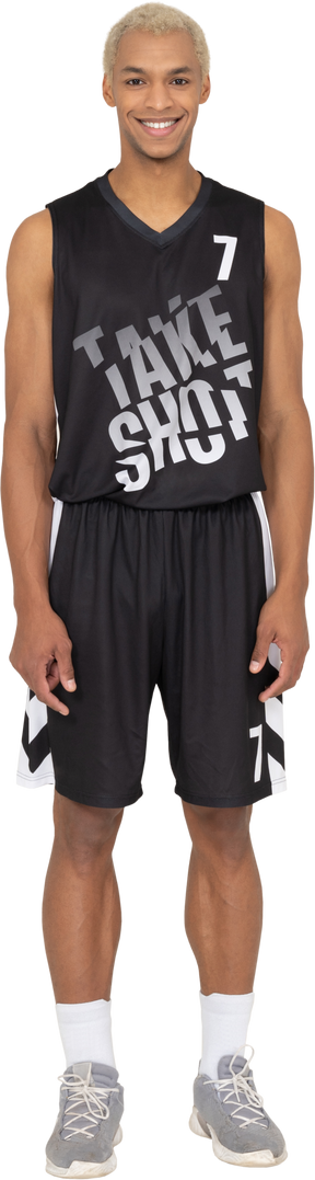 Vista frontale di un giovane giocatore di basket maschio sorridente in piedi immobile