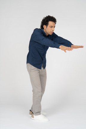 Side view of a man in casual clothes posing with outstretched arms