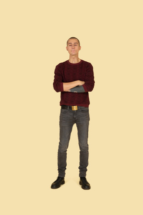 Front view of an offended young man dressed in casual clothes crossing his hands