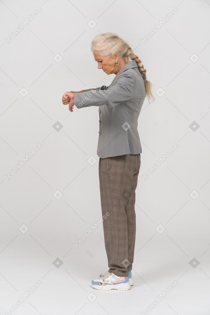 Vista laterale di una vecchia signora in abito che mostra i pollici in giù
