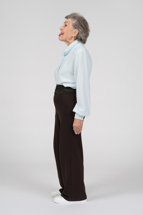 Side view of an old woman sticking tongue out childishly