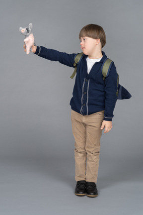 Retrato de un niño pequeño con una mochila sosteniendo un peluche de lechón