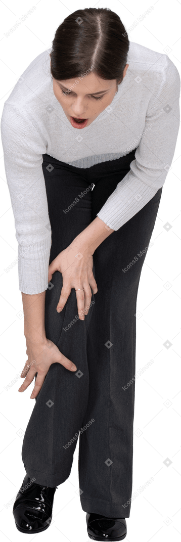 Vista frontale di una giovane donna in abiti da ufficio che tocca il ginocchio