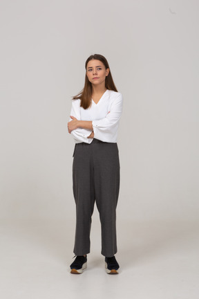 Vista frontal de uma jovem pensativa em roupas de escritório, cruzando os braços