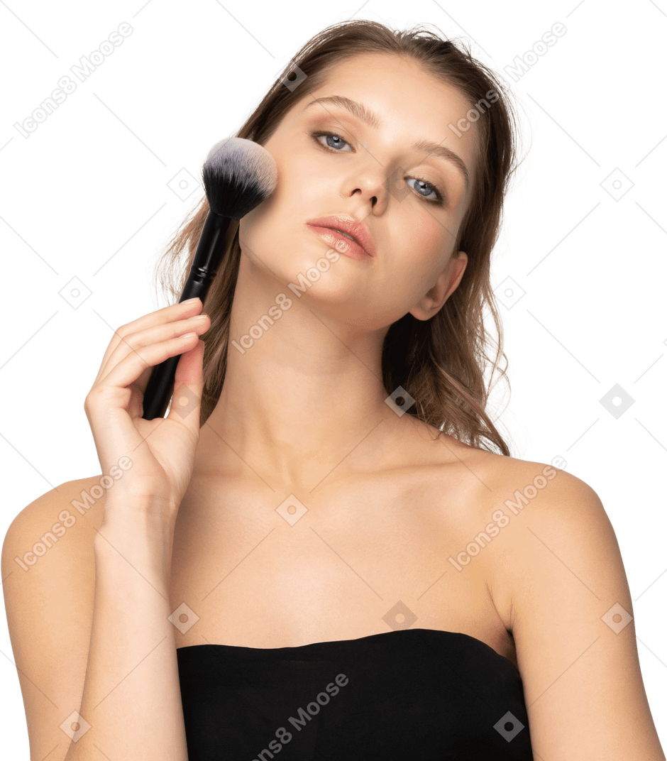 Vista frontale di una giovane donna sensuale con in mano un pennello da trucco