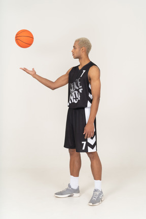 Three-quarter view of a young male basketball player throwing a ball