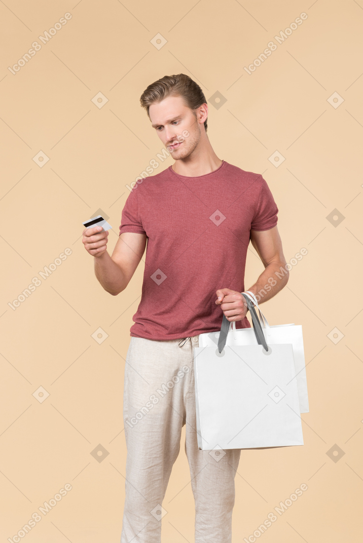 흰색 쇼핑백과 신용 카드를 들고 젊은 남자
