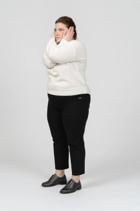 Side view of a plump woman in casual clothes closing ears