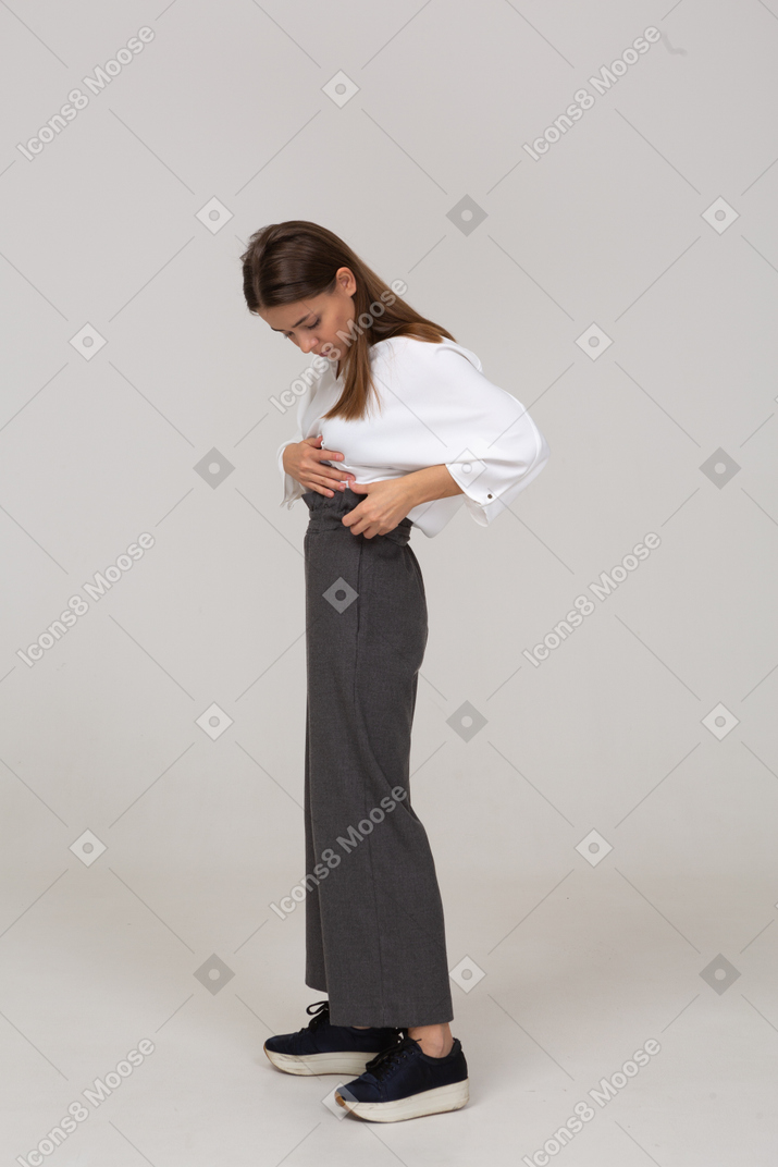 一位身着办公室服装的年轻女士调整裤子的侧视图