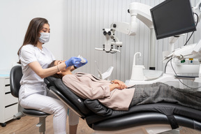 Comprimento total de uma dentista examinando seu paciente em um armário de hospital e segurando um guardanapo