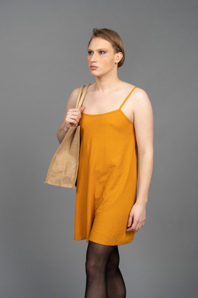 Young person in orange dress walking with bag on shoulder