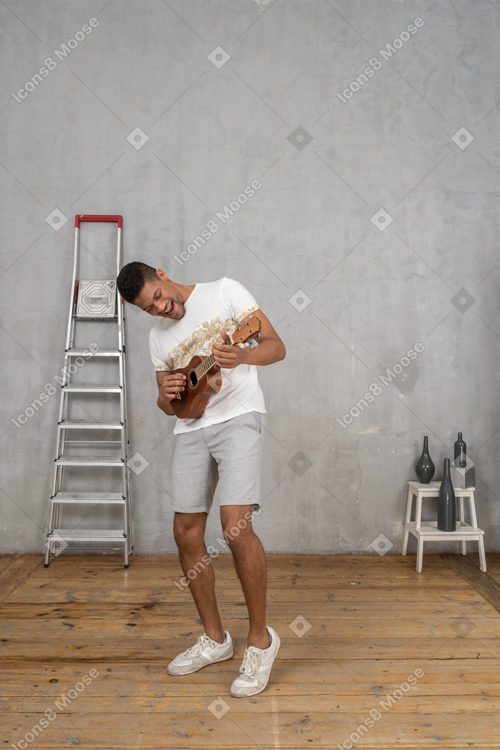 Dreiviertelansicht eines mannes, der sich zur seite lehnt und fröhlich ukulele spielt