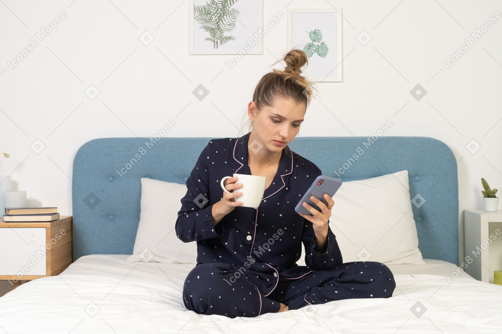 Na frente de uma jovem mulher de pijama sentada na cama com a xícara de café enquanto verifica o instagram